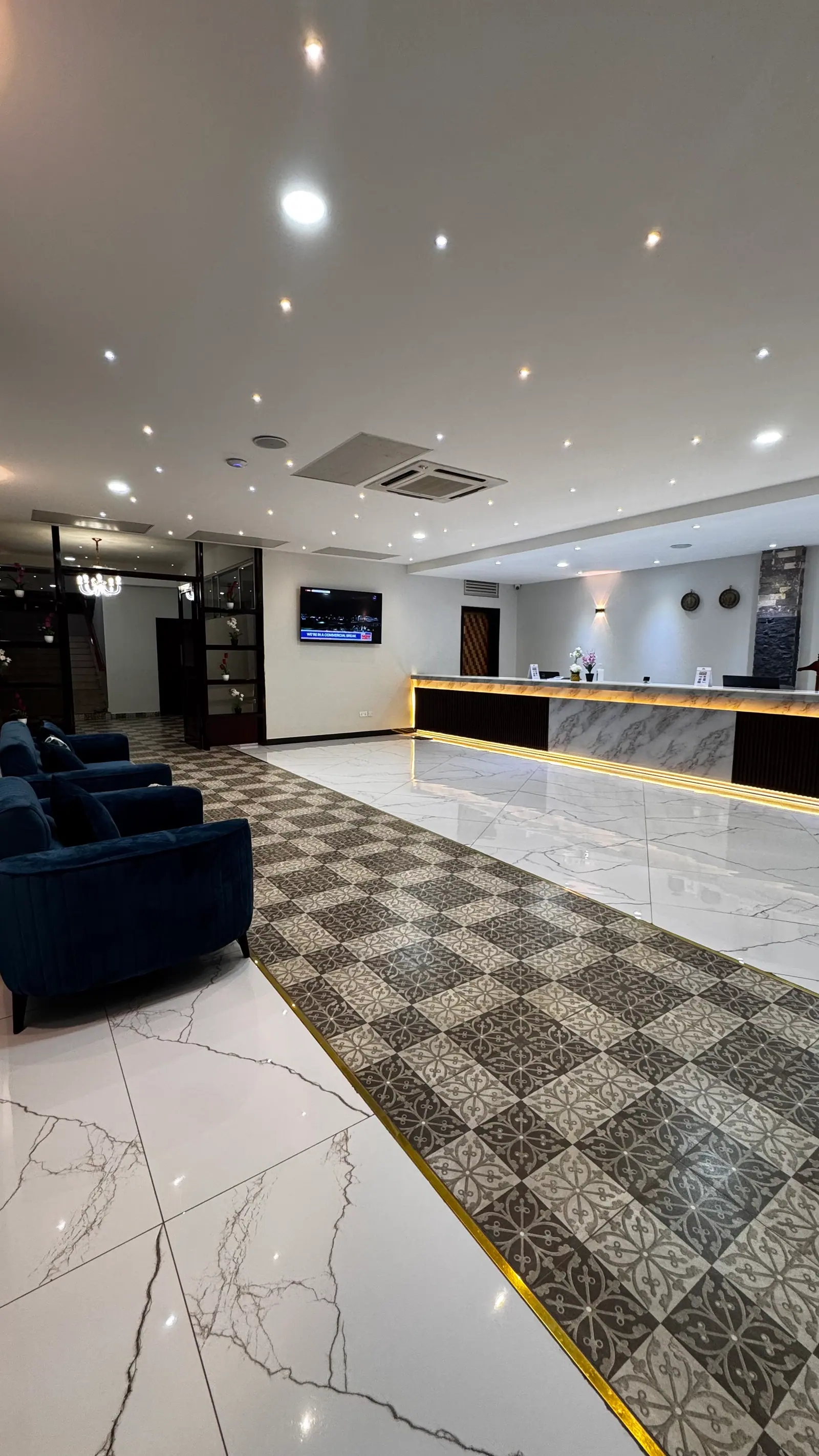 The lobby at Nexus Resorts Hotel Plus — a marble reception desk lit from beneath, velvet armchairs and a chandelier