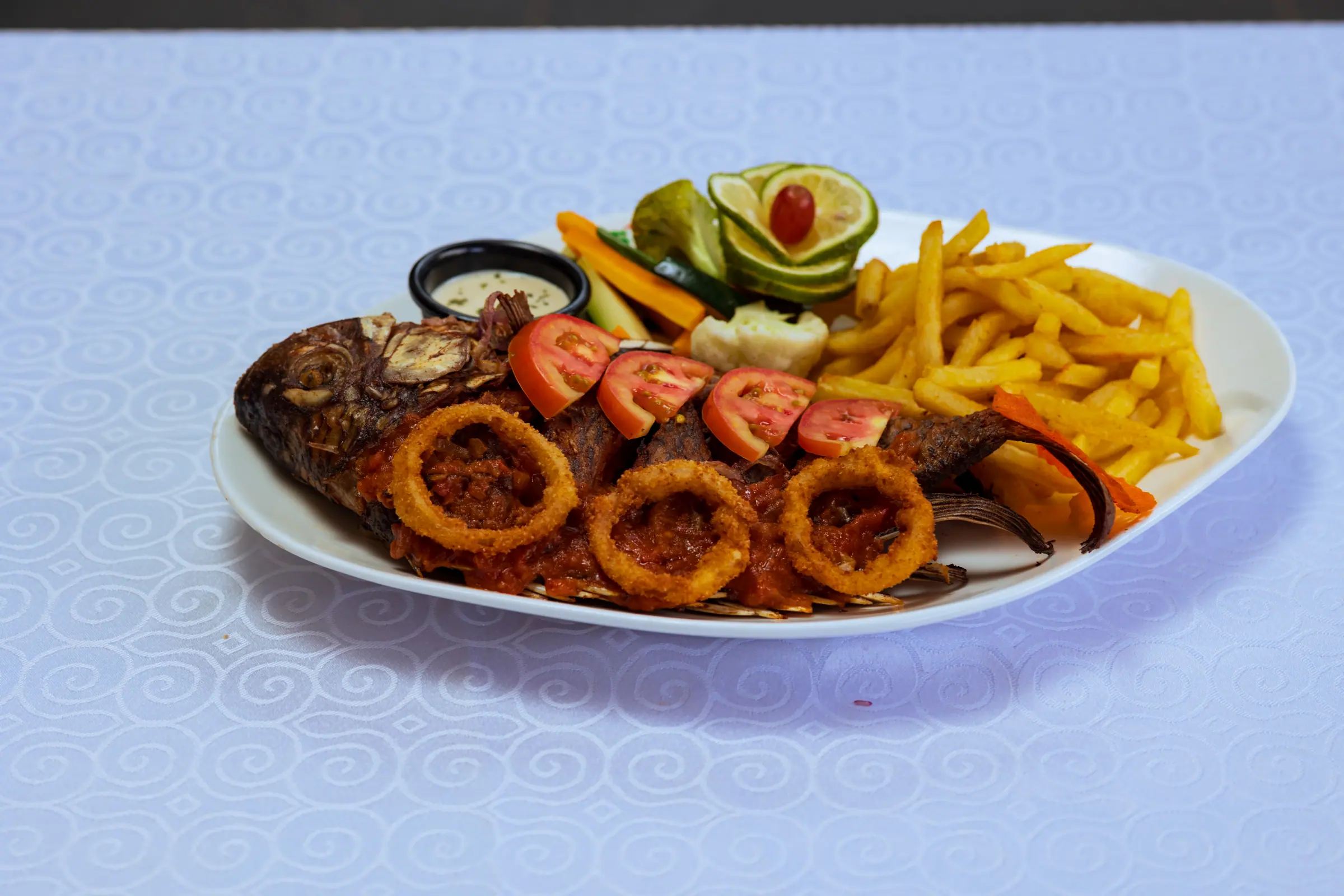 Whole grilled tilapia served with chips and salad